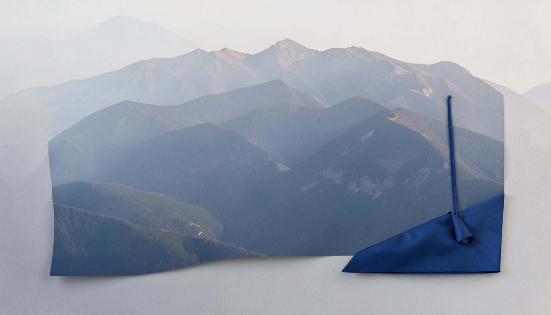 Aerial view of a Balkan mountain range with layered ridges fading into haze under soft morning light